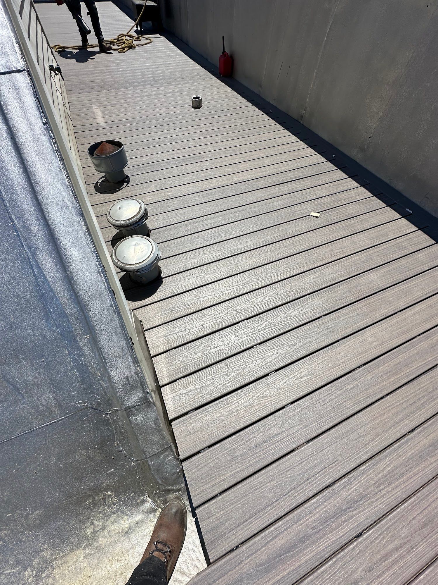 Walkway with several small round objects lined along the left edge beside a wall and railing