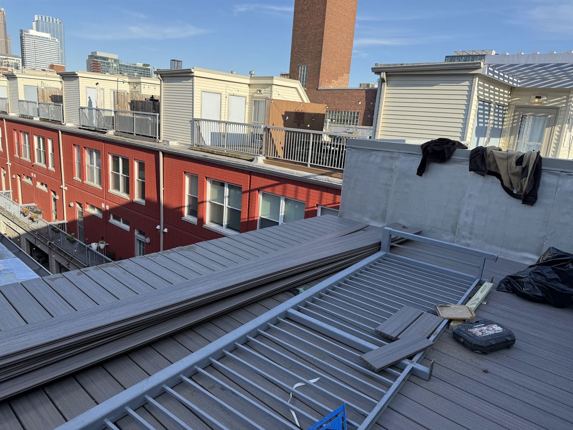 Rooftop with metal decking and tools overlooking red brick buildings in a cityscape