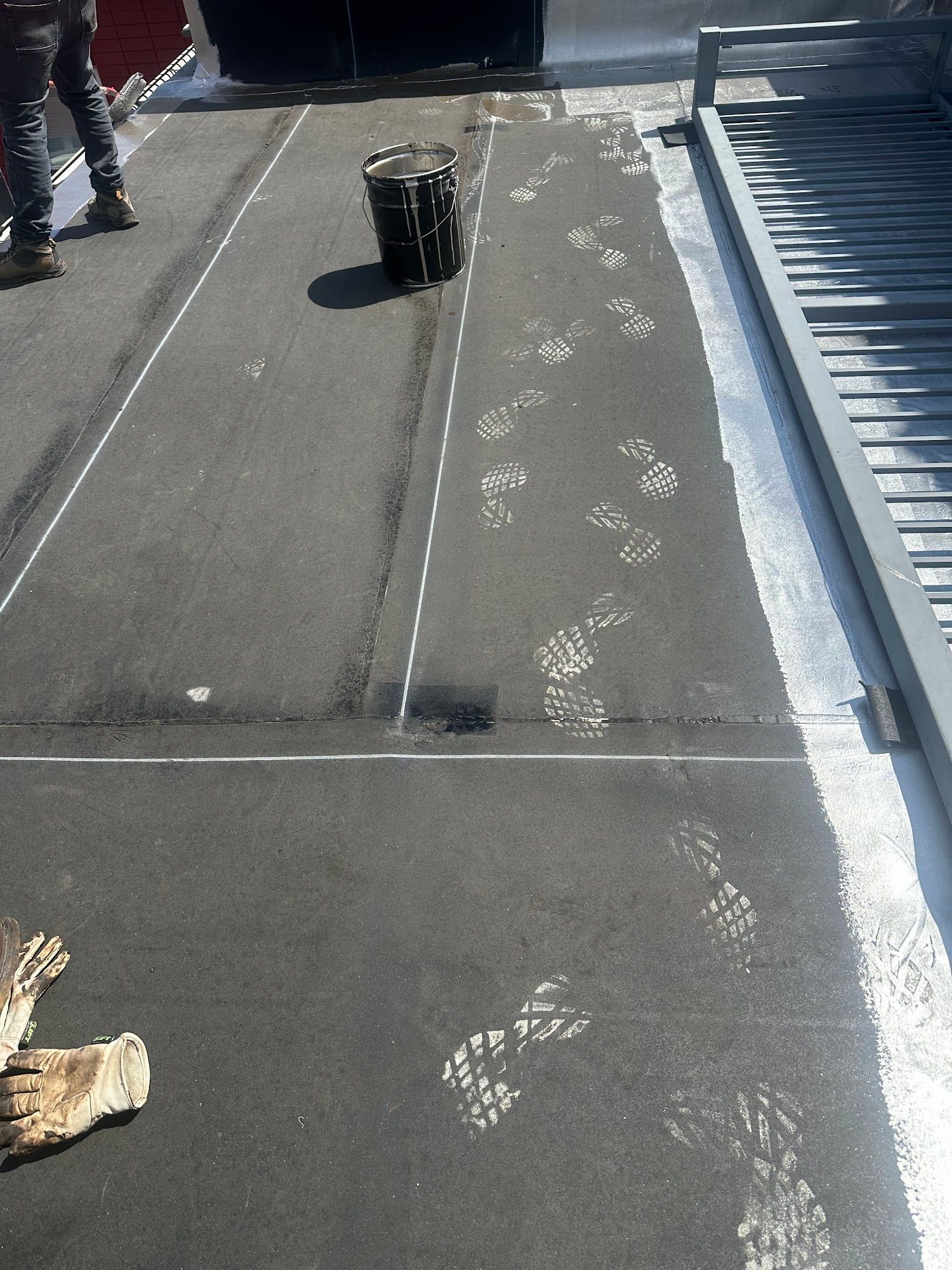 Footprint trail on a rooftop walkway with a black vent and a corrugated metal edge.