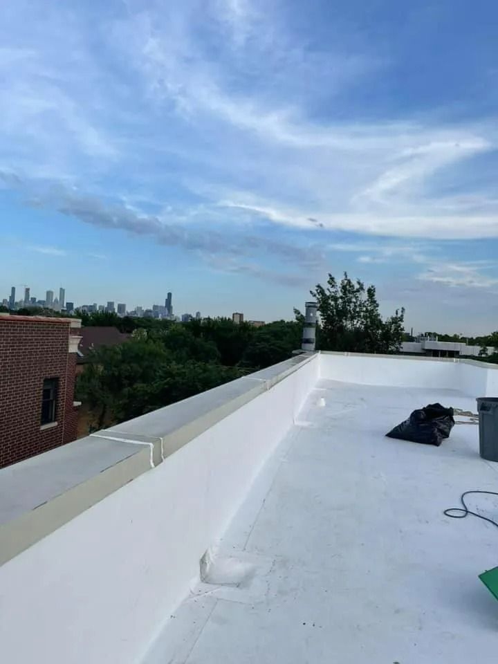 Rooftop with white surface overlooking a city skyline under a blue, cloudy sky