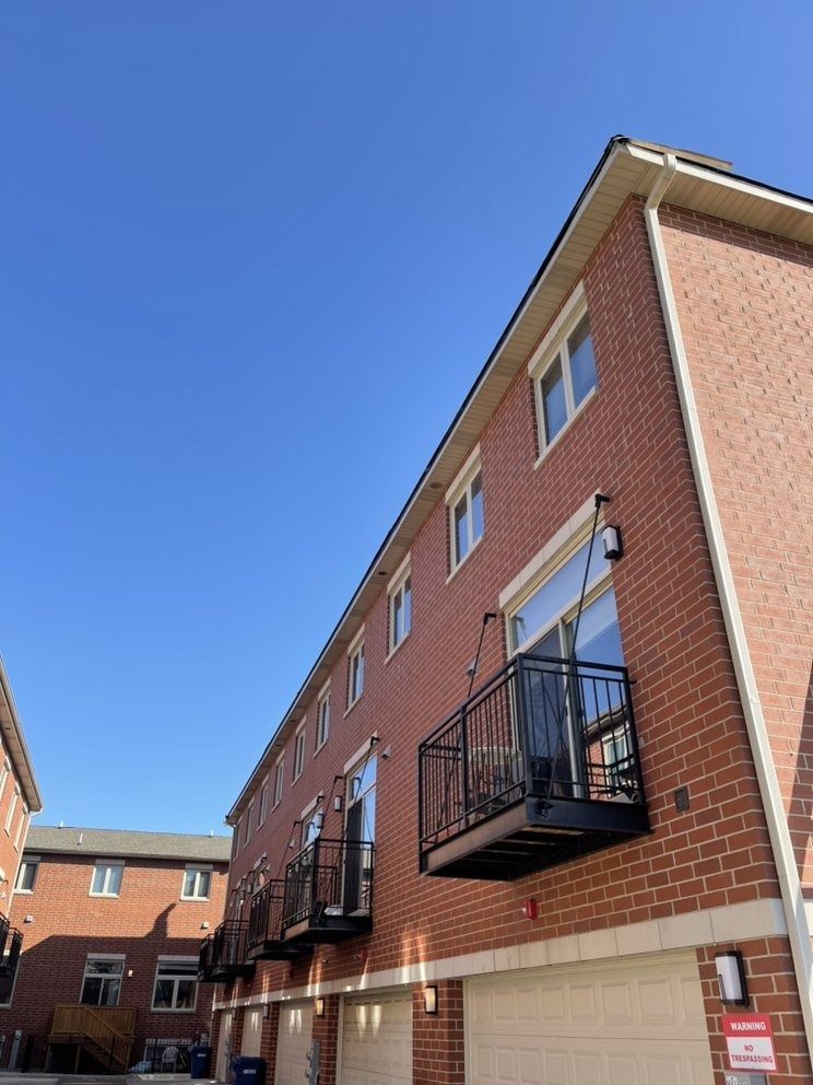 Brick apartment building with black balconies under a clear blue sky