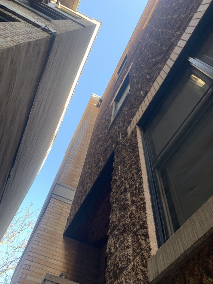 Upward view between tall brick buildings with a blue sky visible above