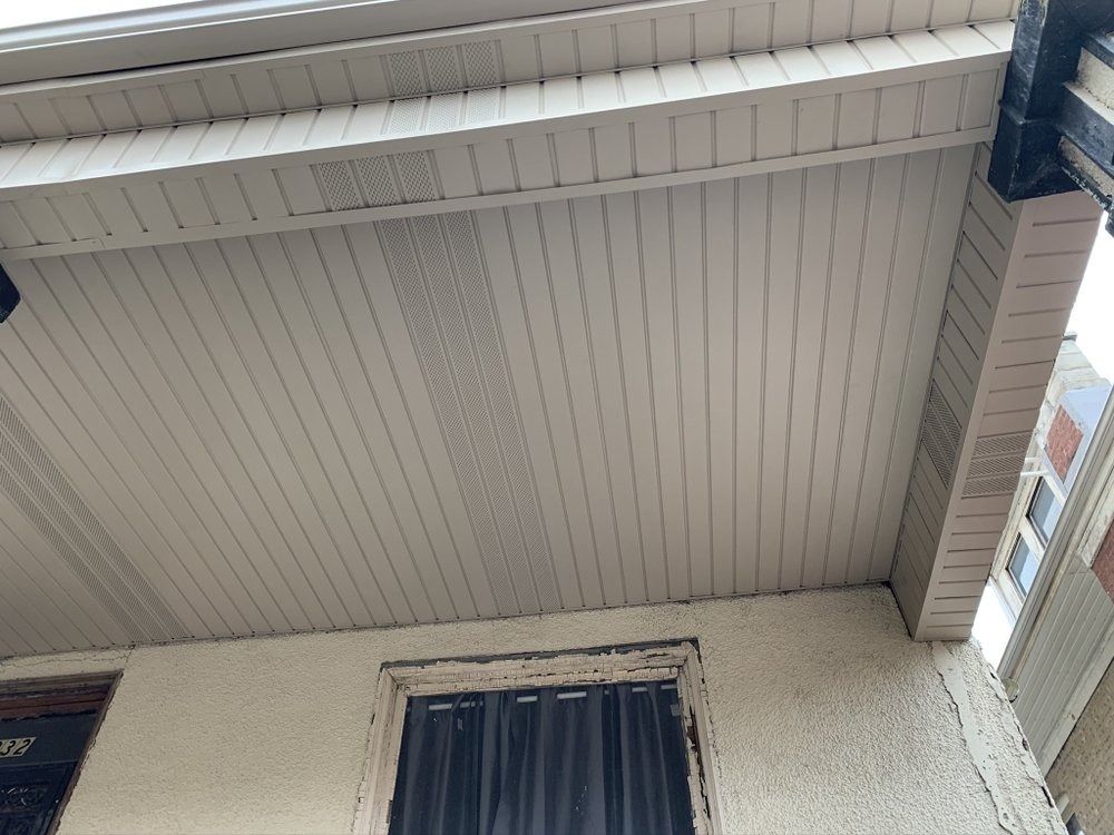 Underside of a white house roof eave above a window and cream exterior wall
