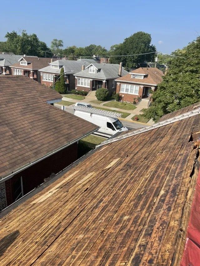 Rooftops of suburban houses and a white van viewed from a weathered roof on a sunny day