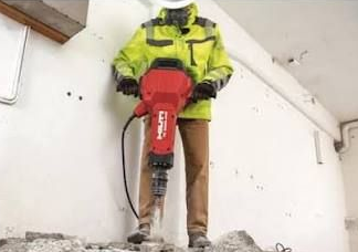 Red HILTI jackhammer kit with wheeled cart, hose, and two chisel bits on white background