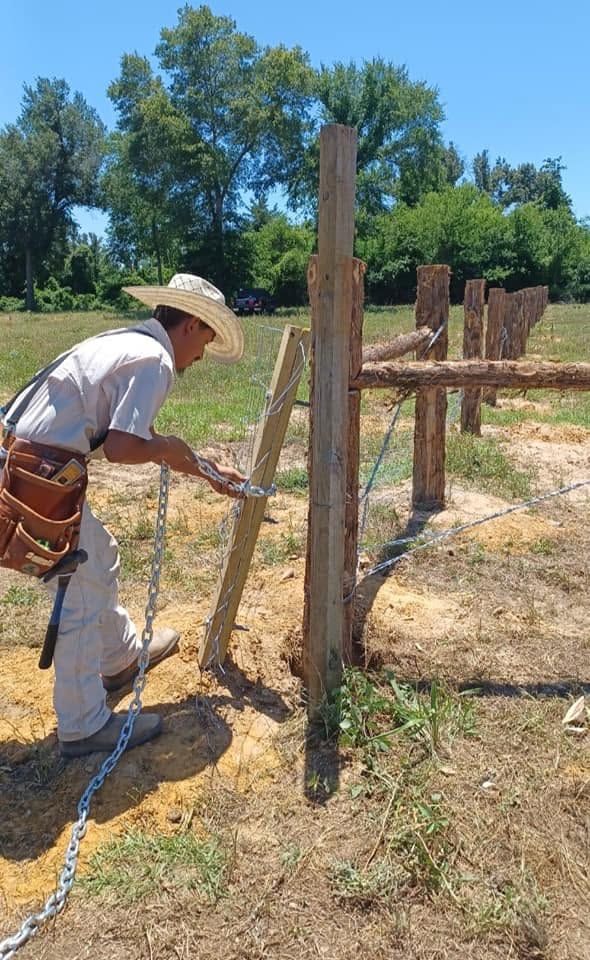 Person building a wooden fence in a dry field on a sunny day