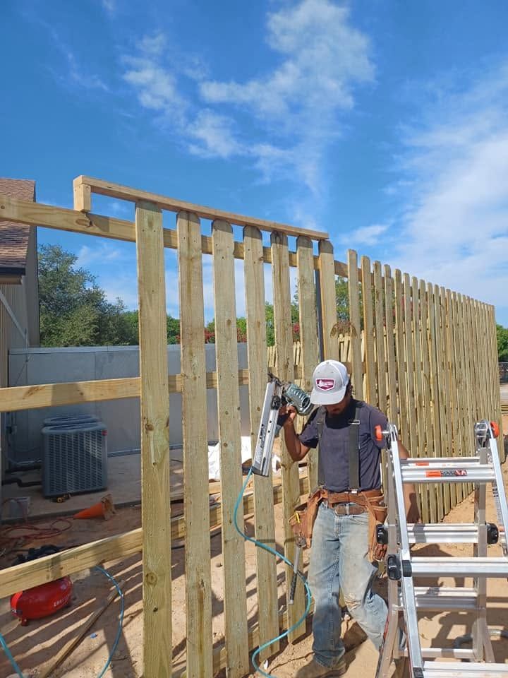 Worker installing wooden wall framing on a construction site under a blue sky.