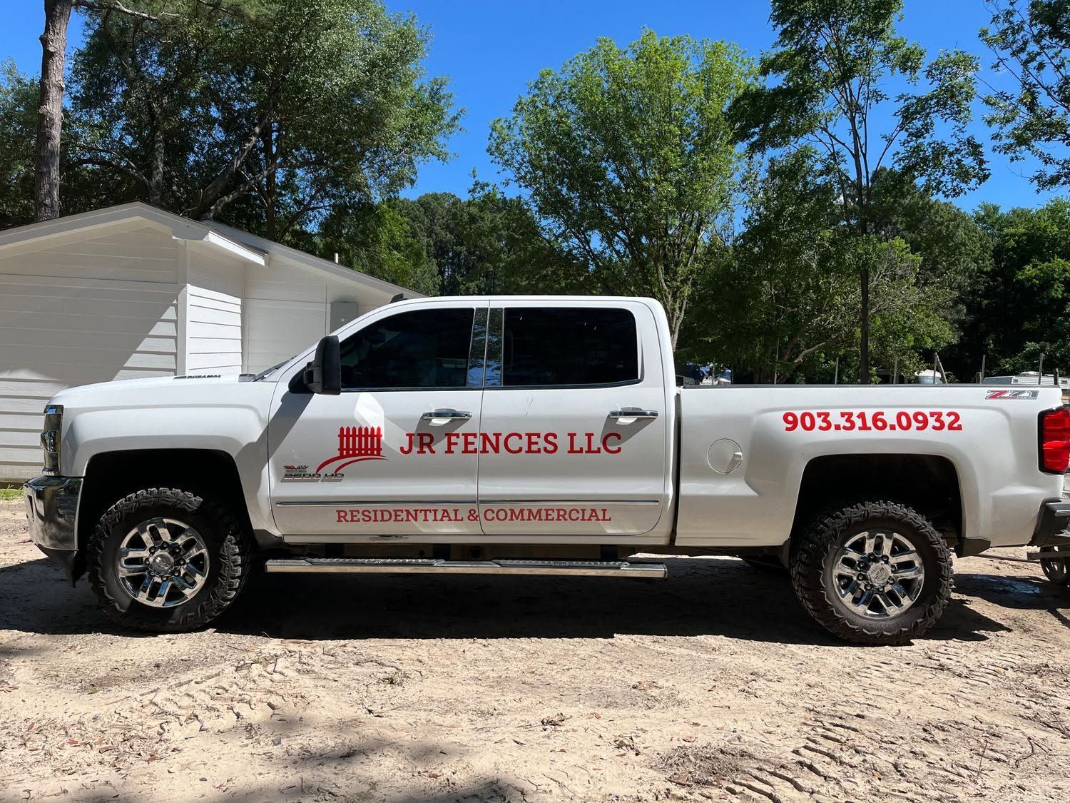 White pickup truck with JR Fences LLC branding parked outdoors on a sunny day