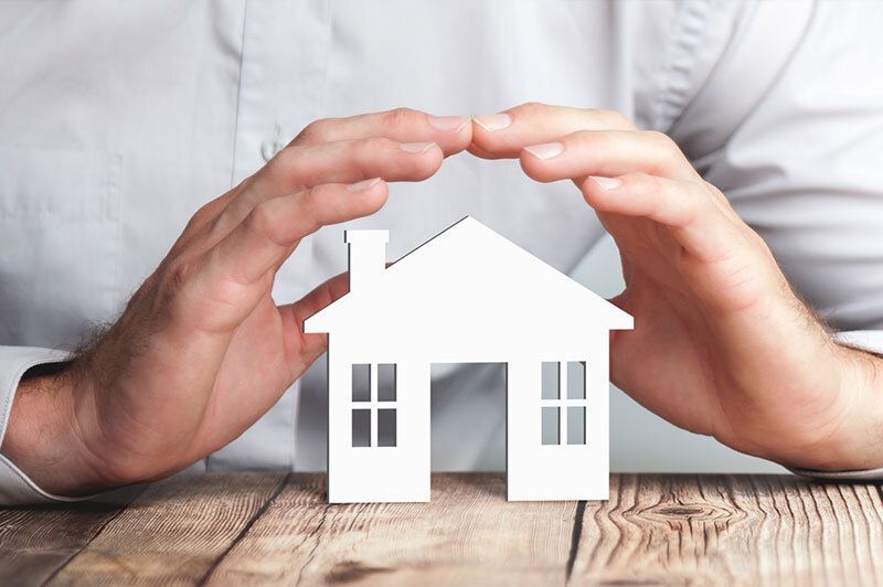 close up of hands protecting a house representing home insurance 