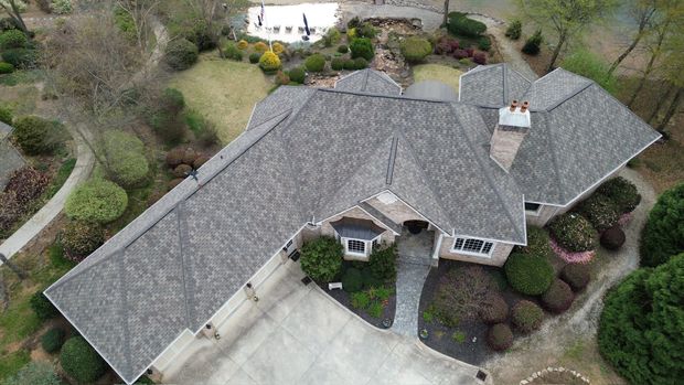 White metal roof with multiple vents, viewed from above, with trees and buildings in the background