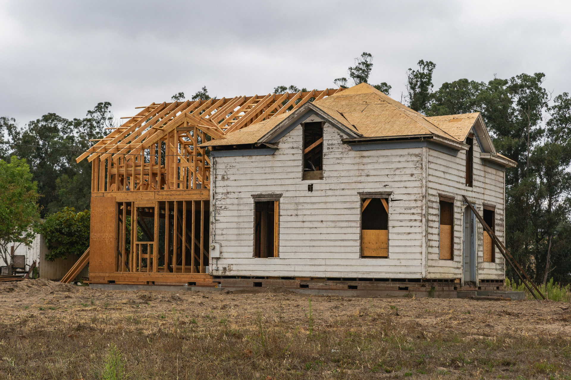 Partially built white house with exposed wooden framing and roof under construction