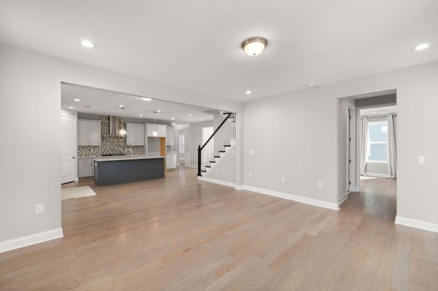 Bright sunroom with wraparound floor-to-ceiling windows, white trim, and views of a wooded deck.