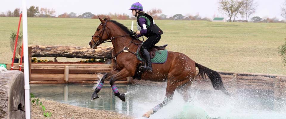 a person is riding a horse through a body of water .