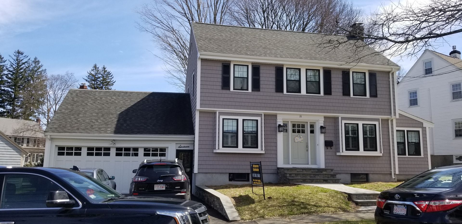 A house with cars parked in front of it on a sunny day.