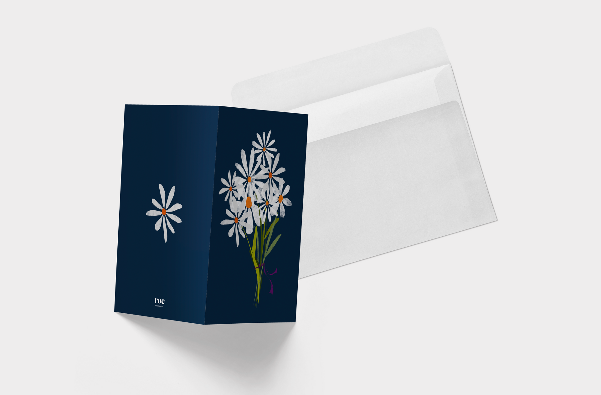 A blue card with white daisies on it is sitting next to a white envelope.