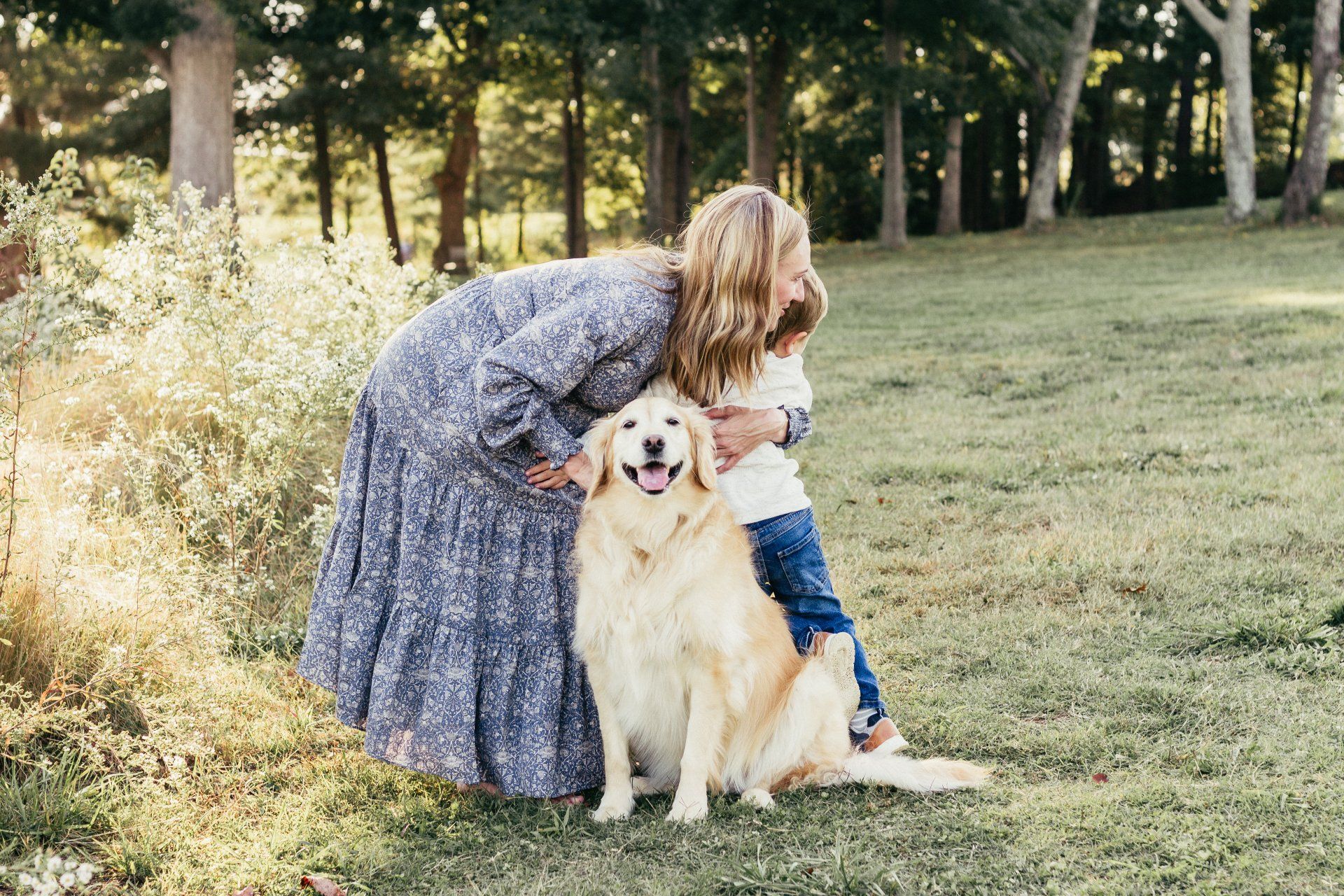 A woman and child are petting a dog in a field.
