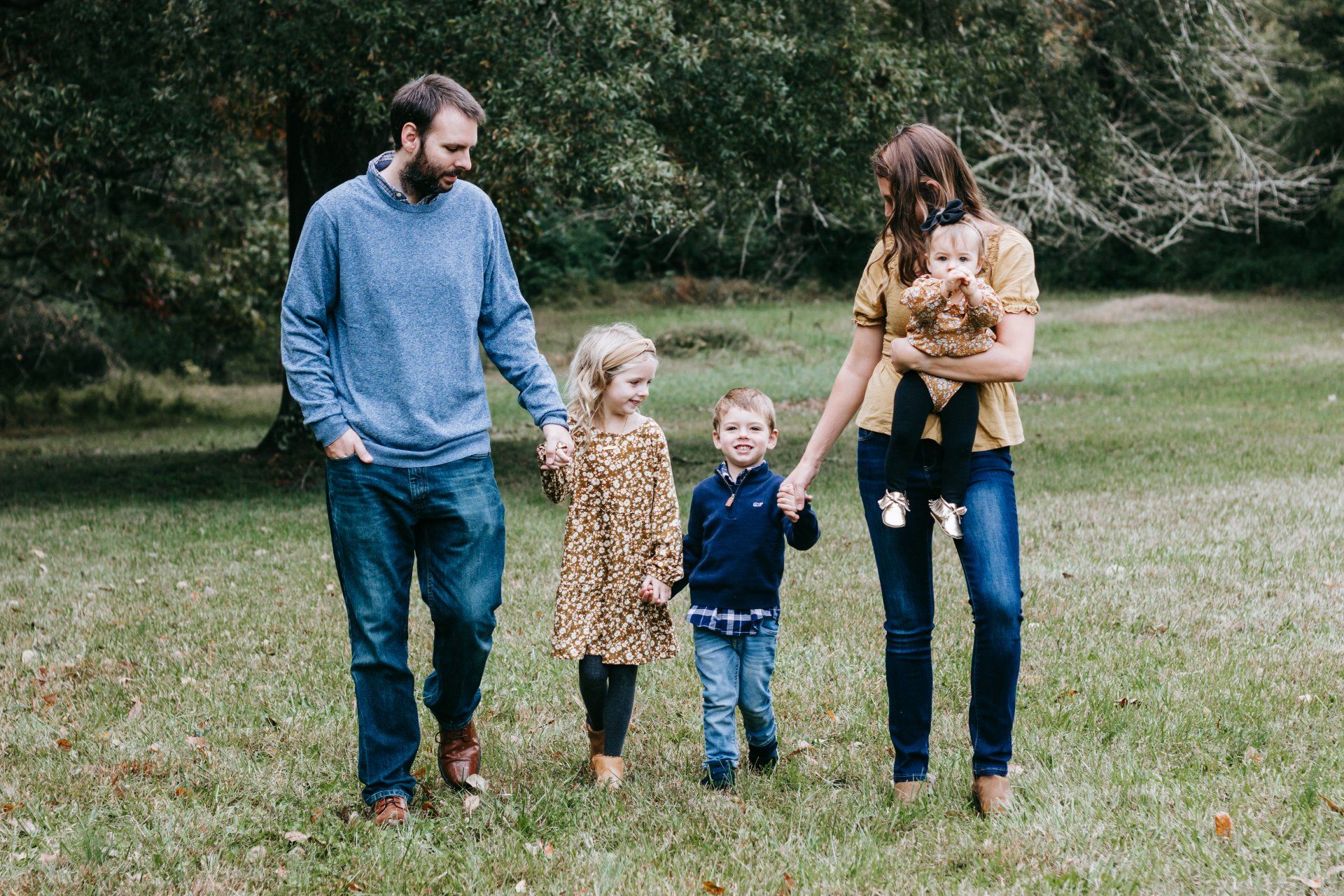A family is walking through a park holding hands.