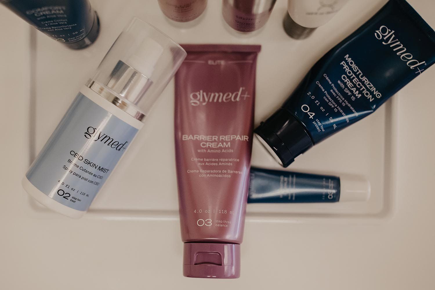 Assorted skincare tubes and bottles arranged in a tray on a light surface.
