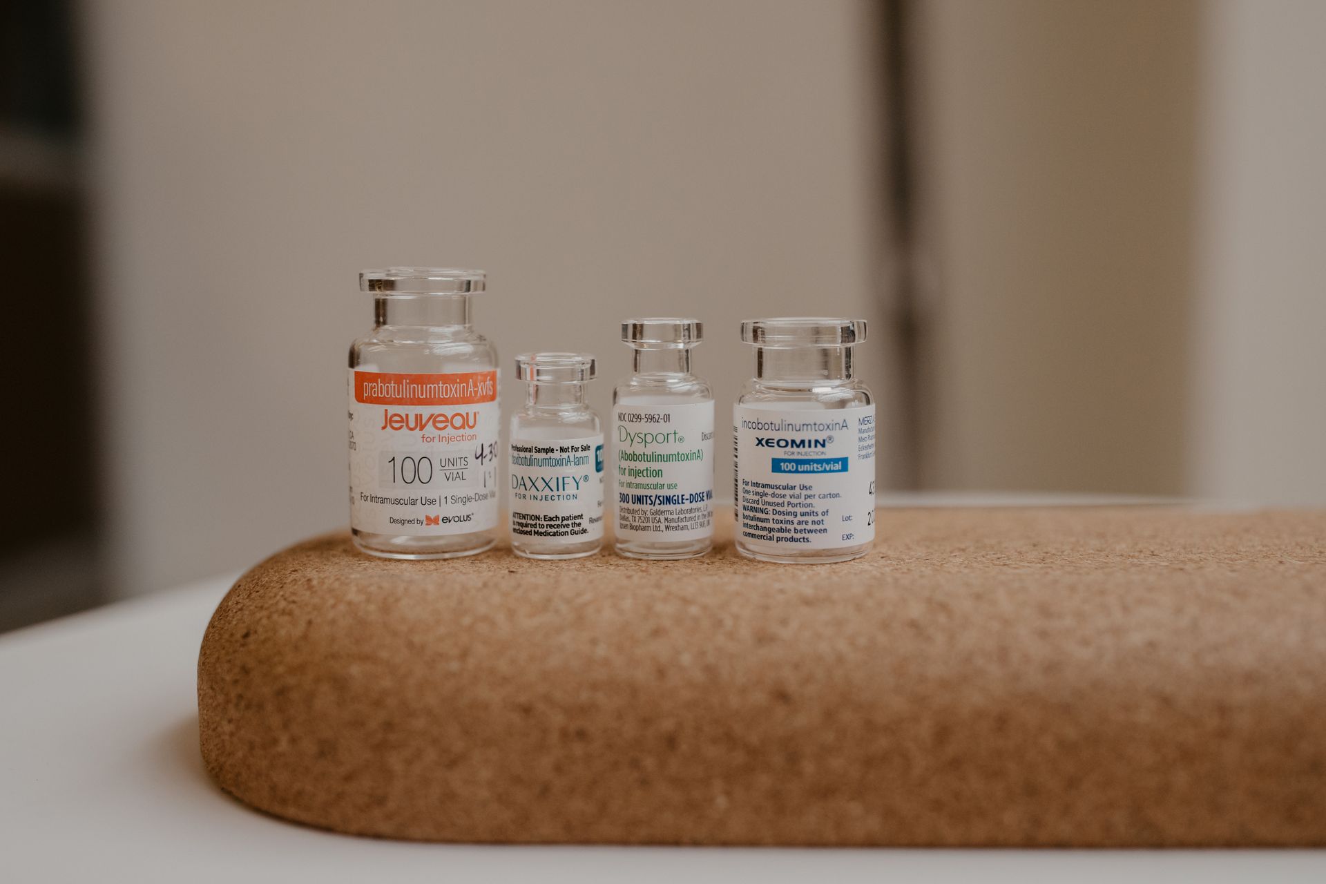 Three small medicine vials on a beige surface, with one larger vial in front.