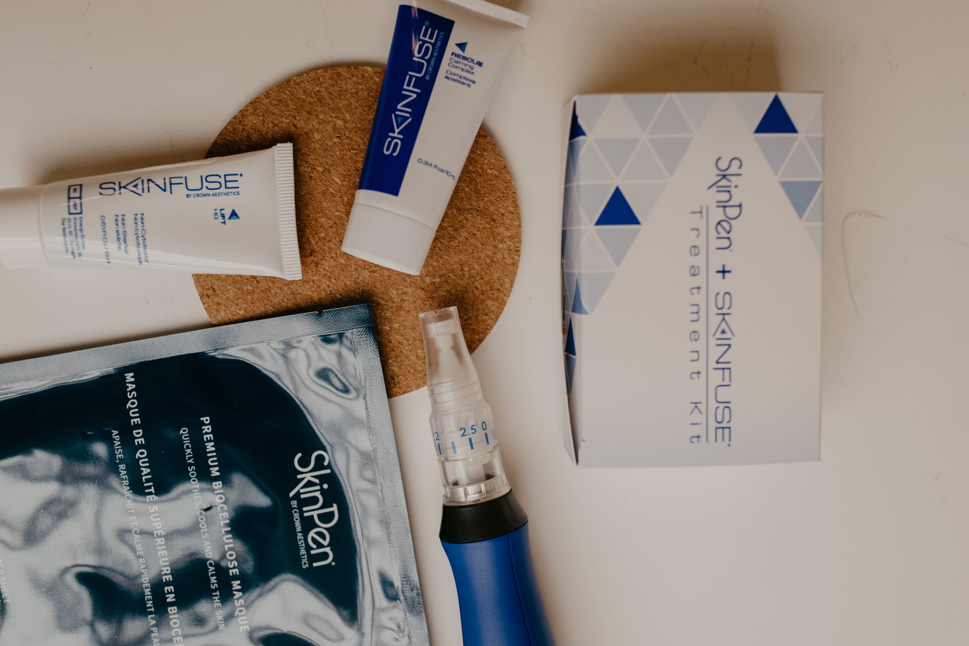 SkinPen treatment kit, including microneedling device, skincare tubes, and a mask, arranged on a light background.