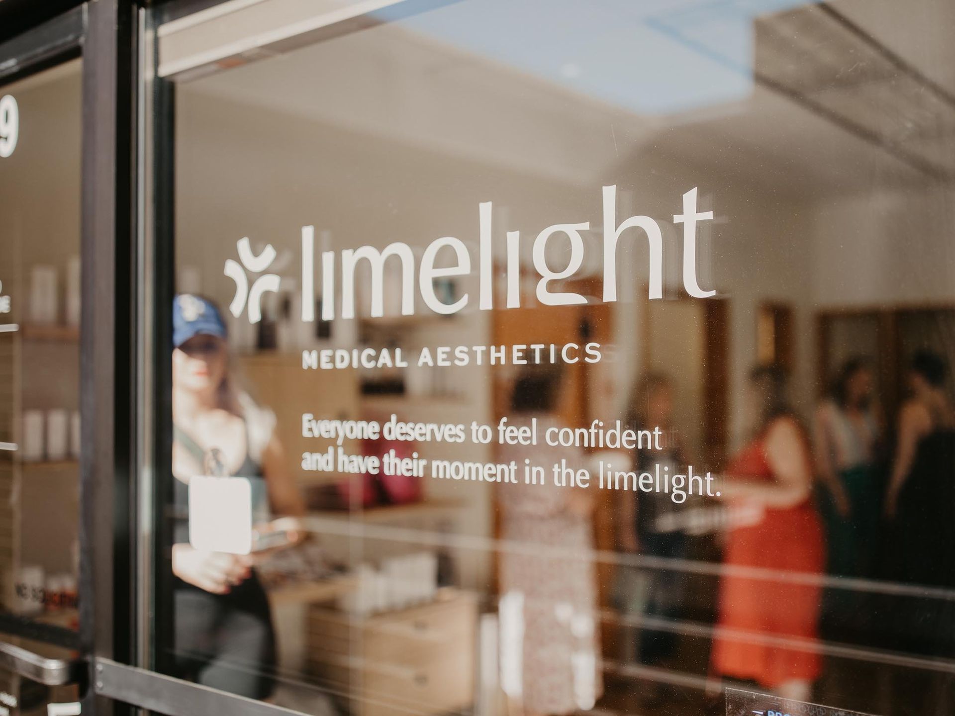 Glass door with white “limelight medical aesthetics” logo and people visible inside the clinic