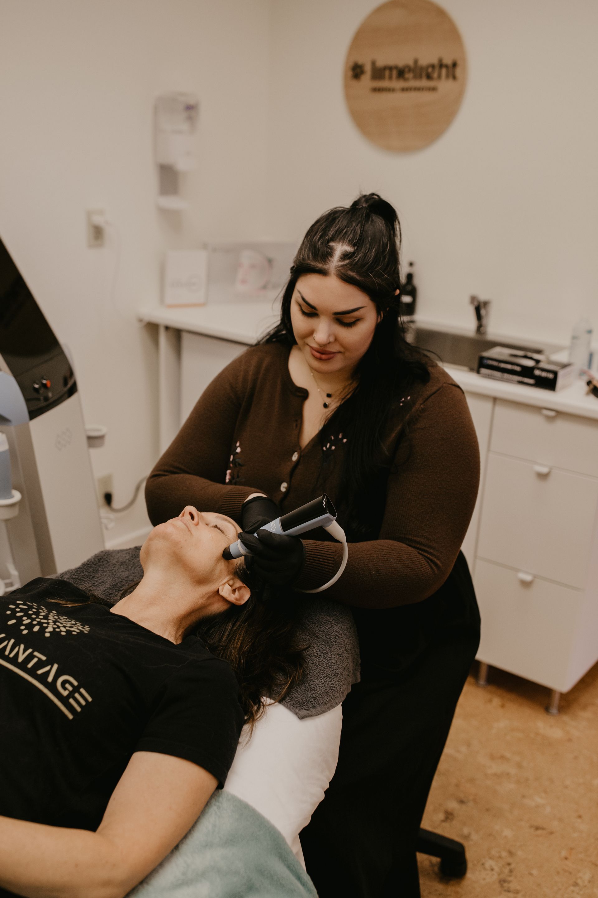Dentist wearing black gloves examining a patient reclined in a dental chair in a clinic room