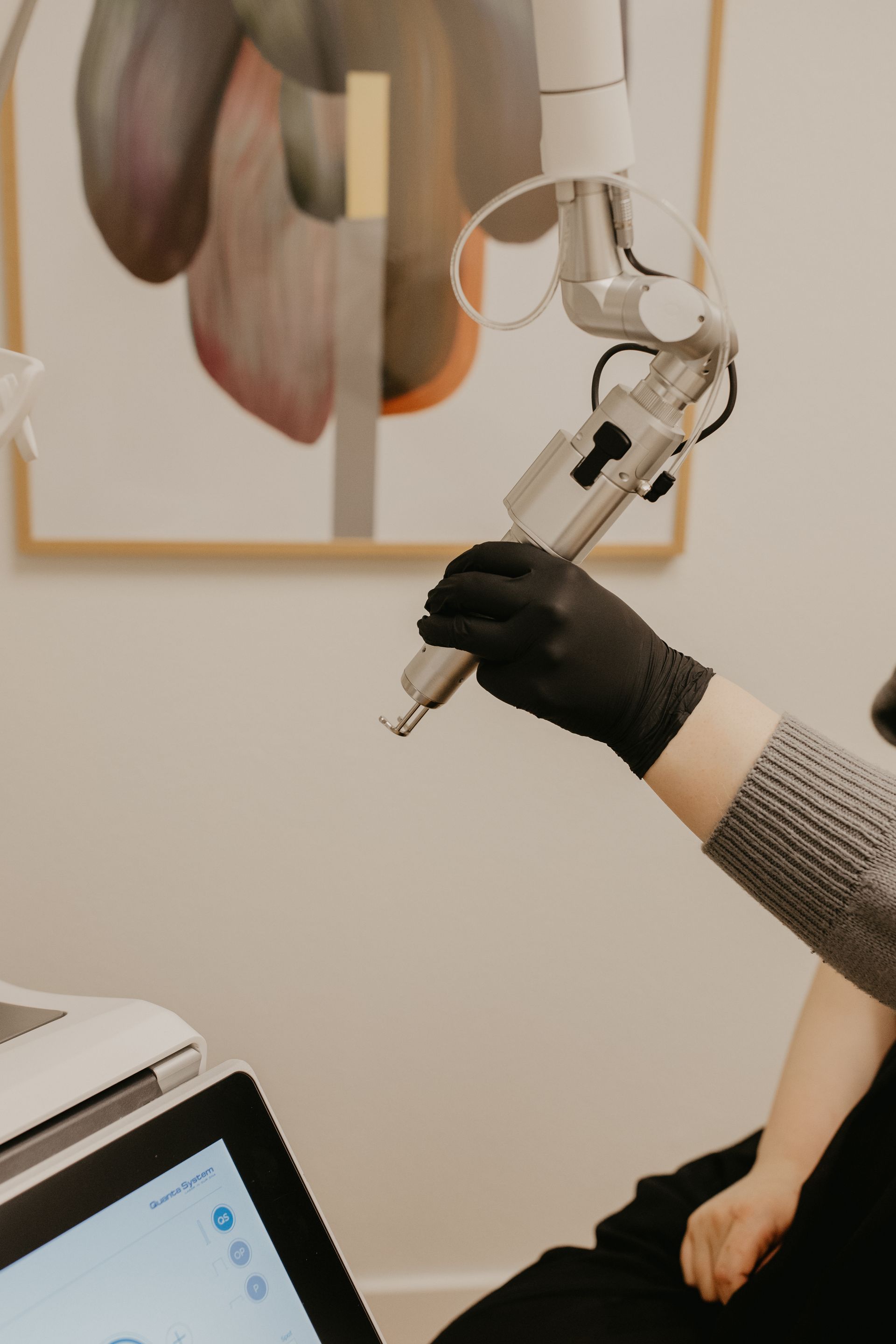 Gloved hand operating a robotic arm beside a laptop in a lab or office setting