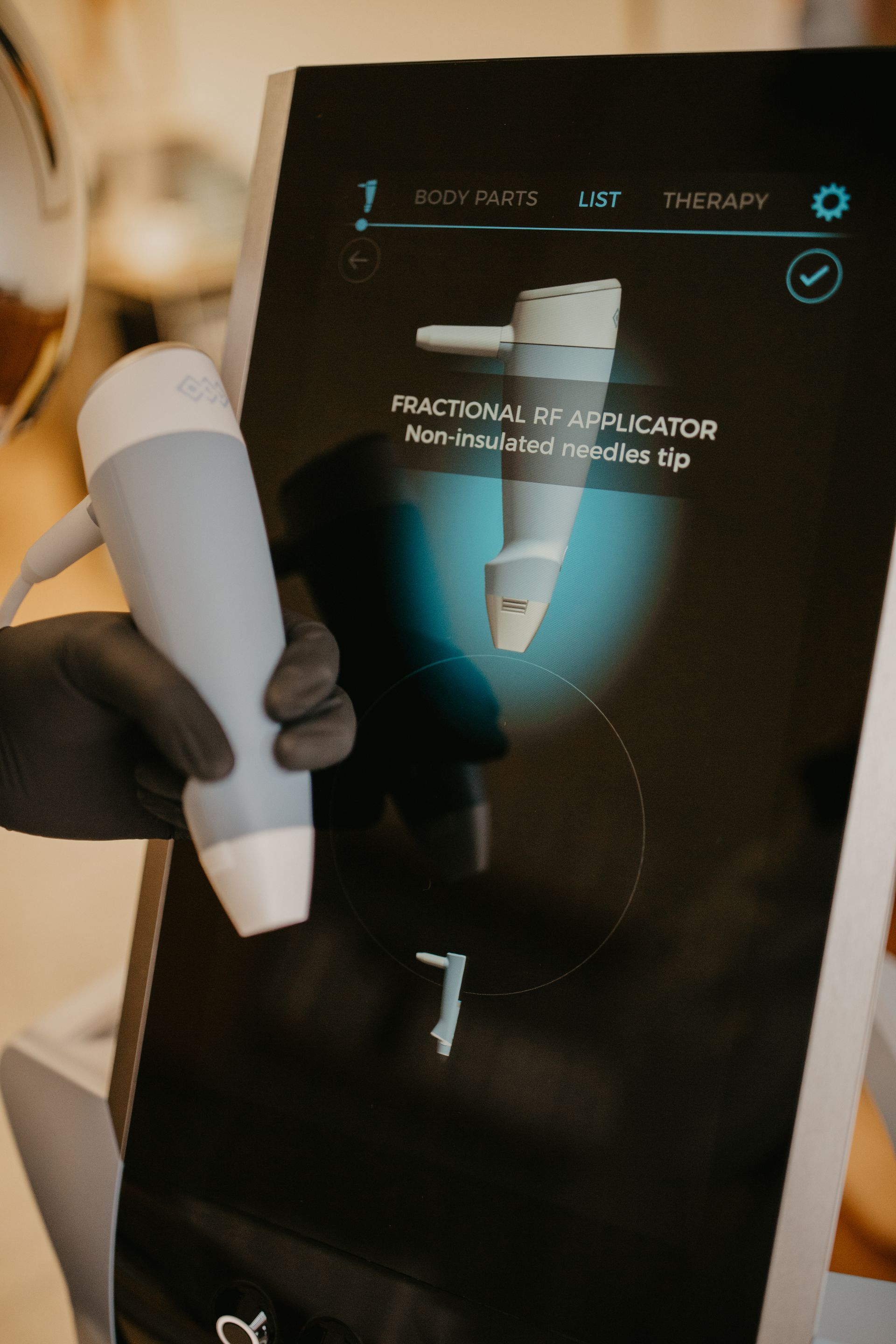Person holding a white handheld device near a touchscreen display with a medical scan image.