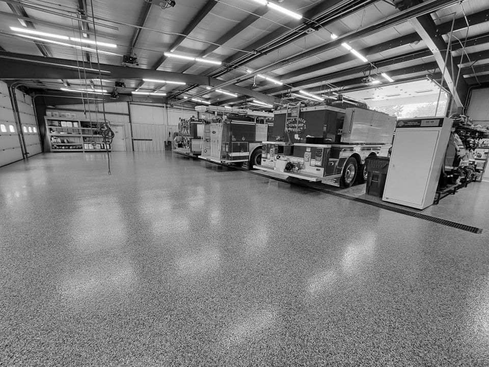 A black and white photo of a garage with fire trucks parked in it.
