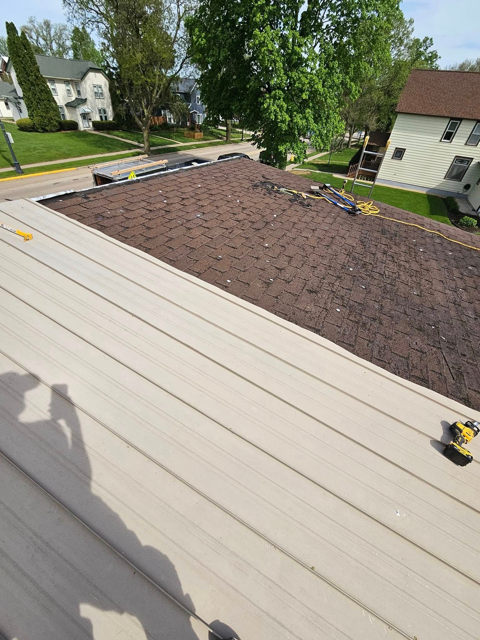 Rooftop with dark gravel and light metal panels, viewed from above on a sunny day.