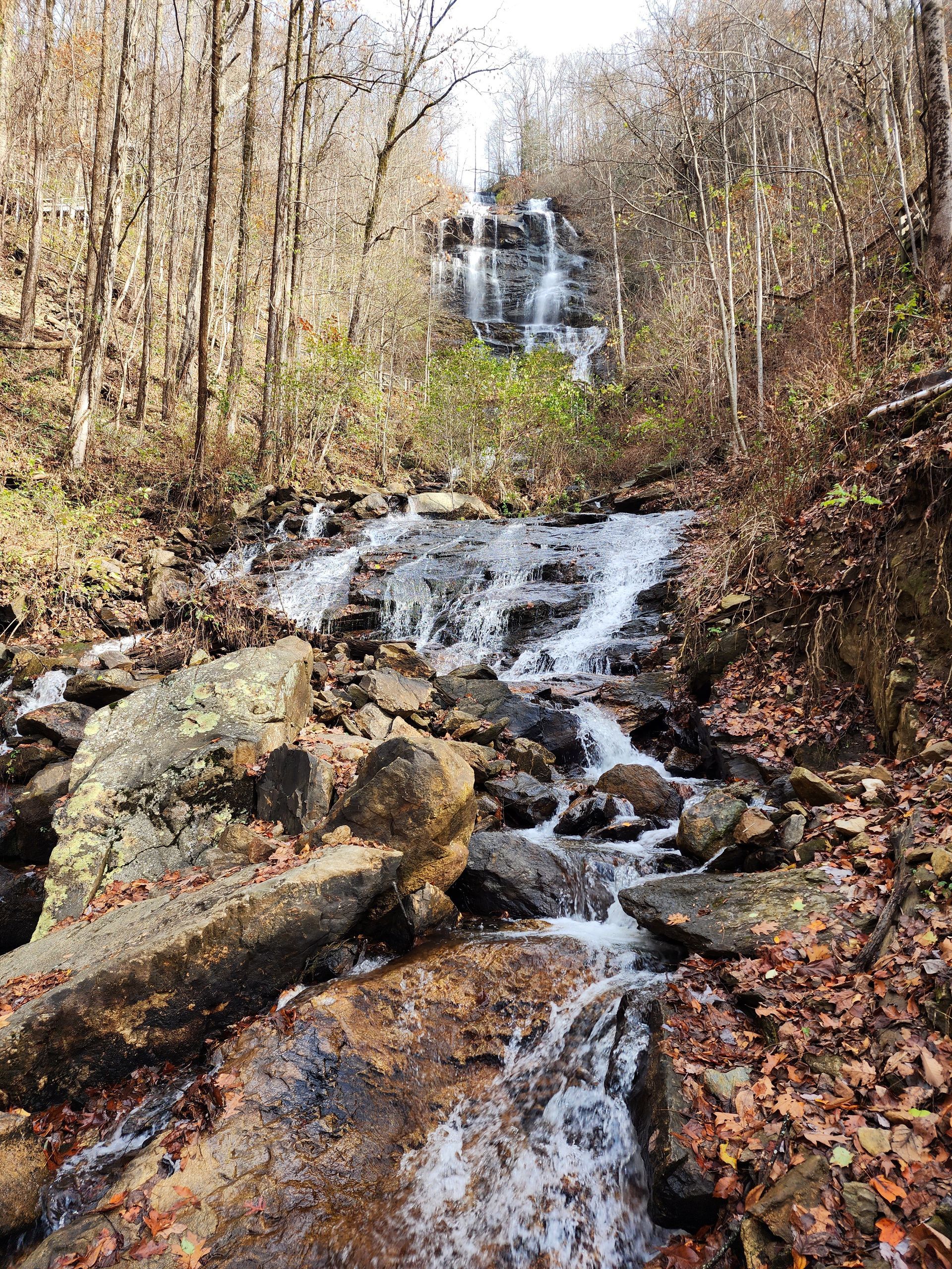 Rocky woodland stream cascading down a leaf-covered hillside in autumn