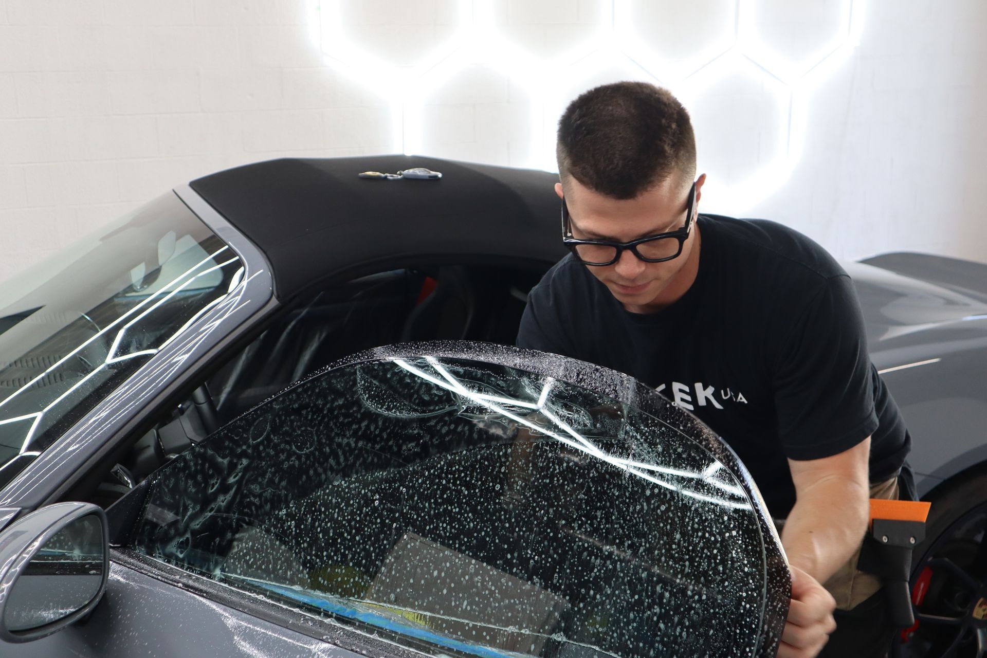 A man is wrapping a car window with a film.