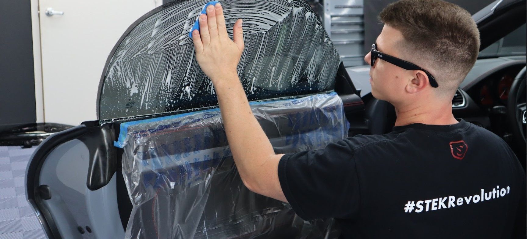A man is applying a film to the side of a car.