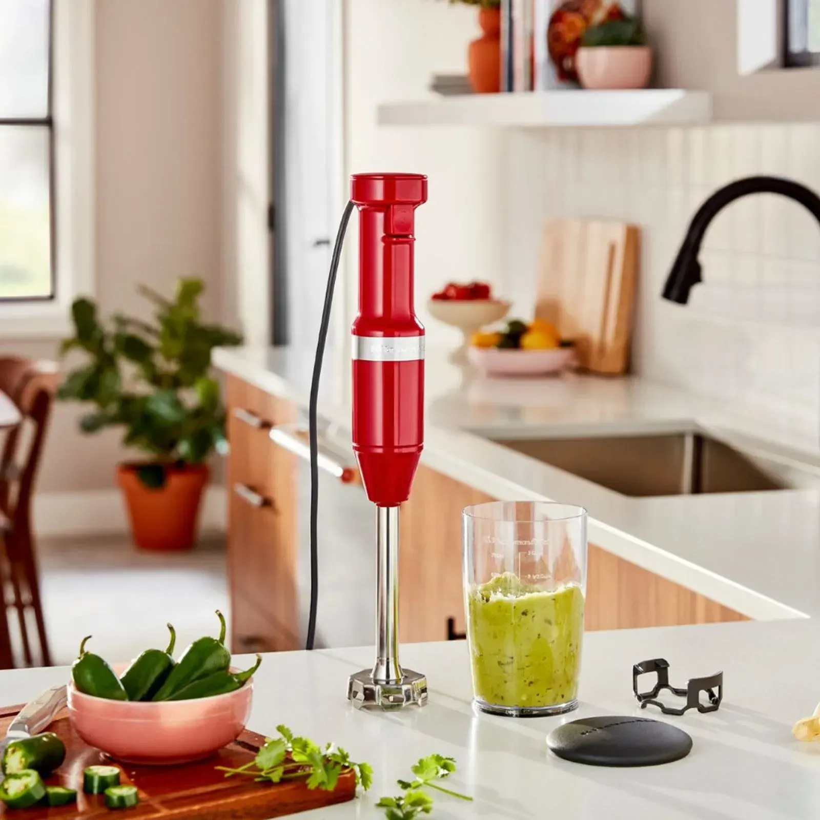 Uma varinha mágica vermelha está em um balcão da cozinha ao lado de um copo de smoothie