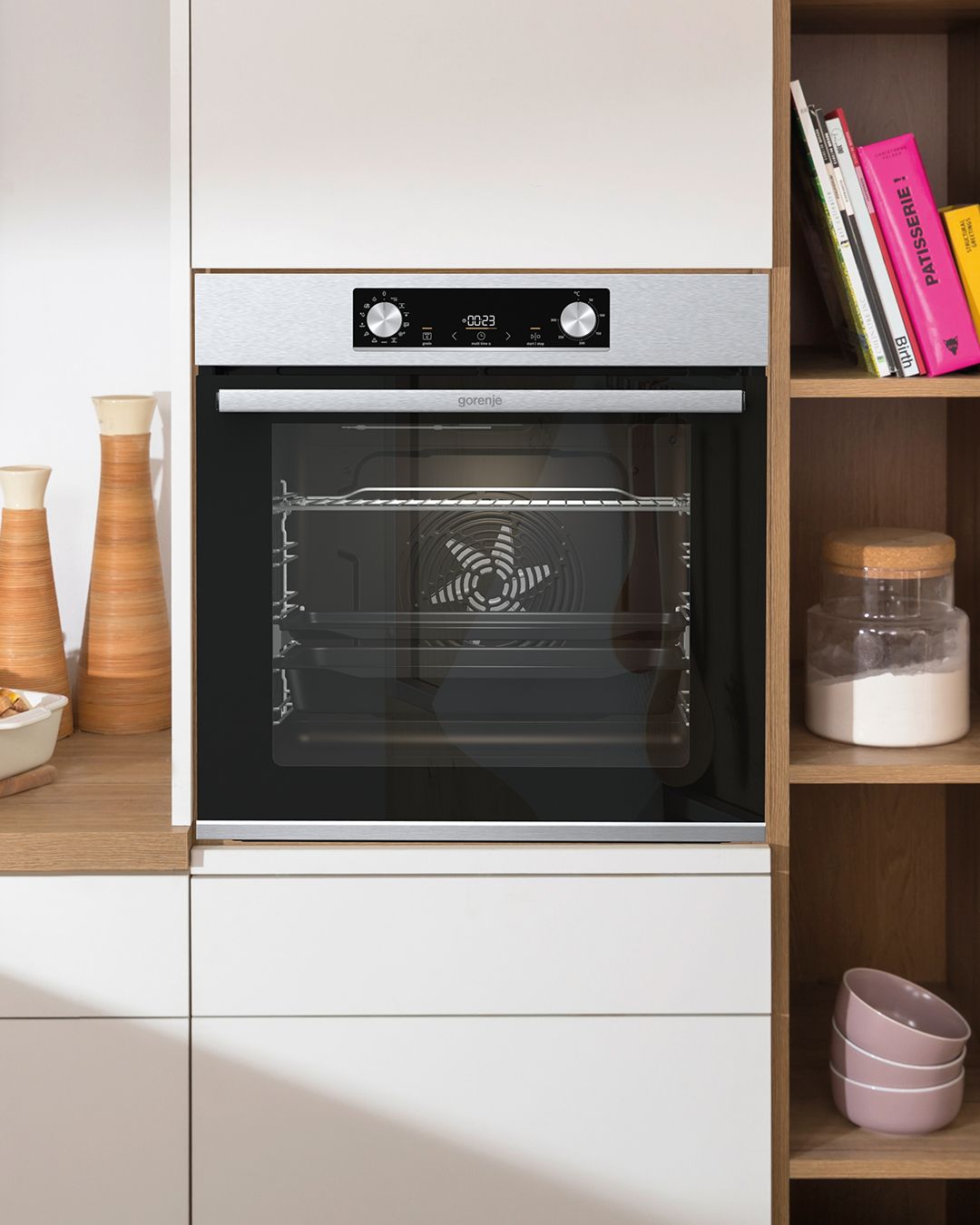 Um forno de aço inoxidável está em uma cozinha ao lado de uma estante.