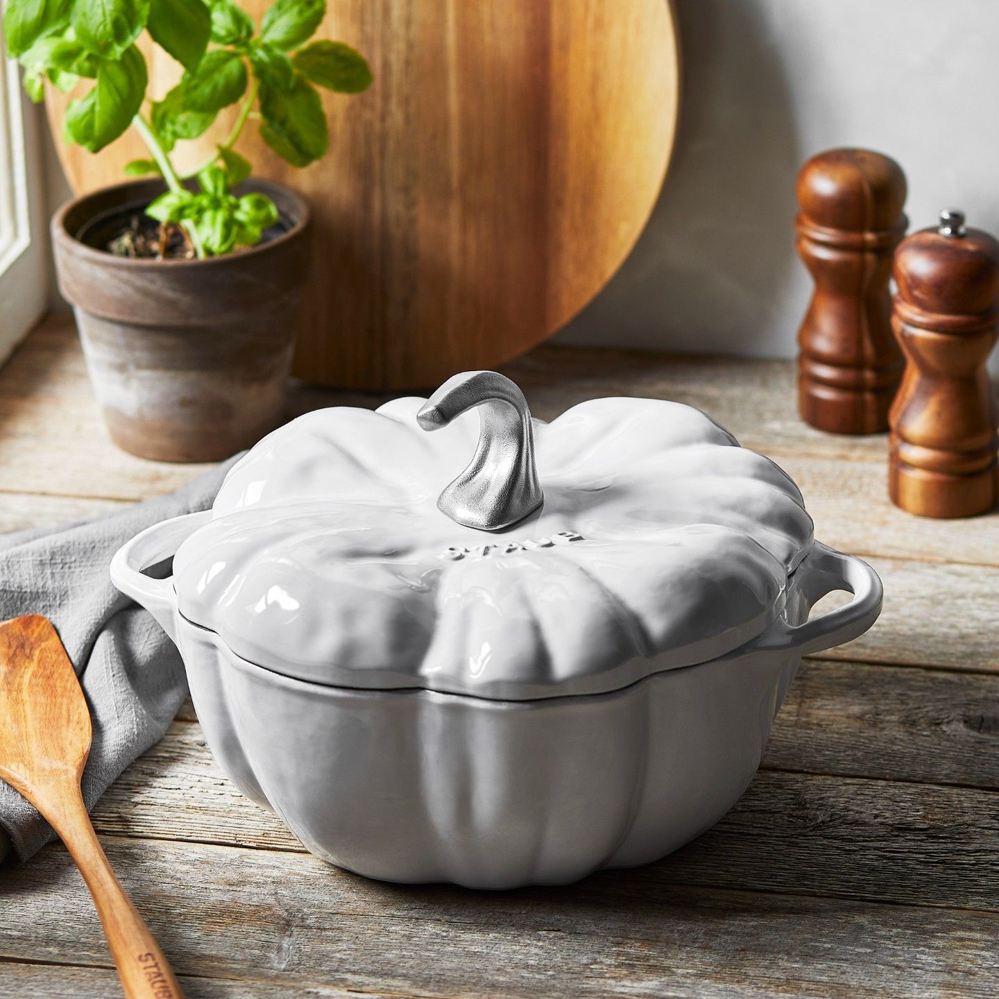 Um pote branco em forma de abóbora está sobre uma mesa de madeira.