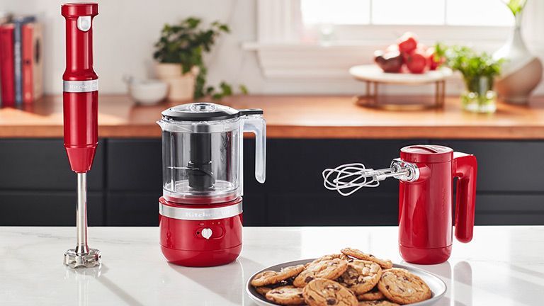 Um balcão de cozinha com um prato de biscoitos, um liquidificador e uma batedeira.