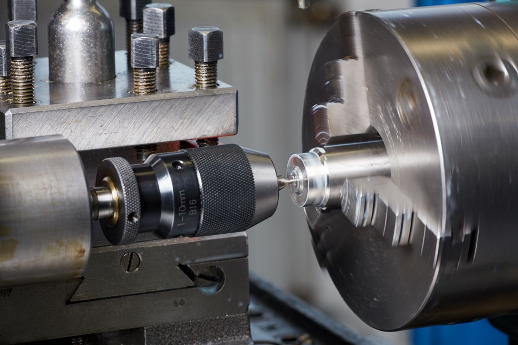 A machine is cutting a piece of metal on a lathe.