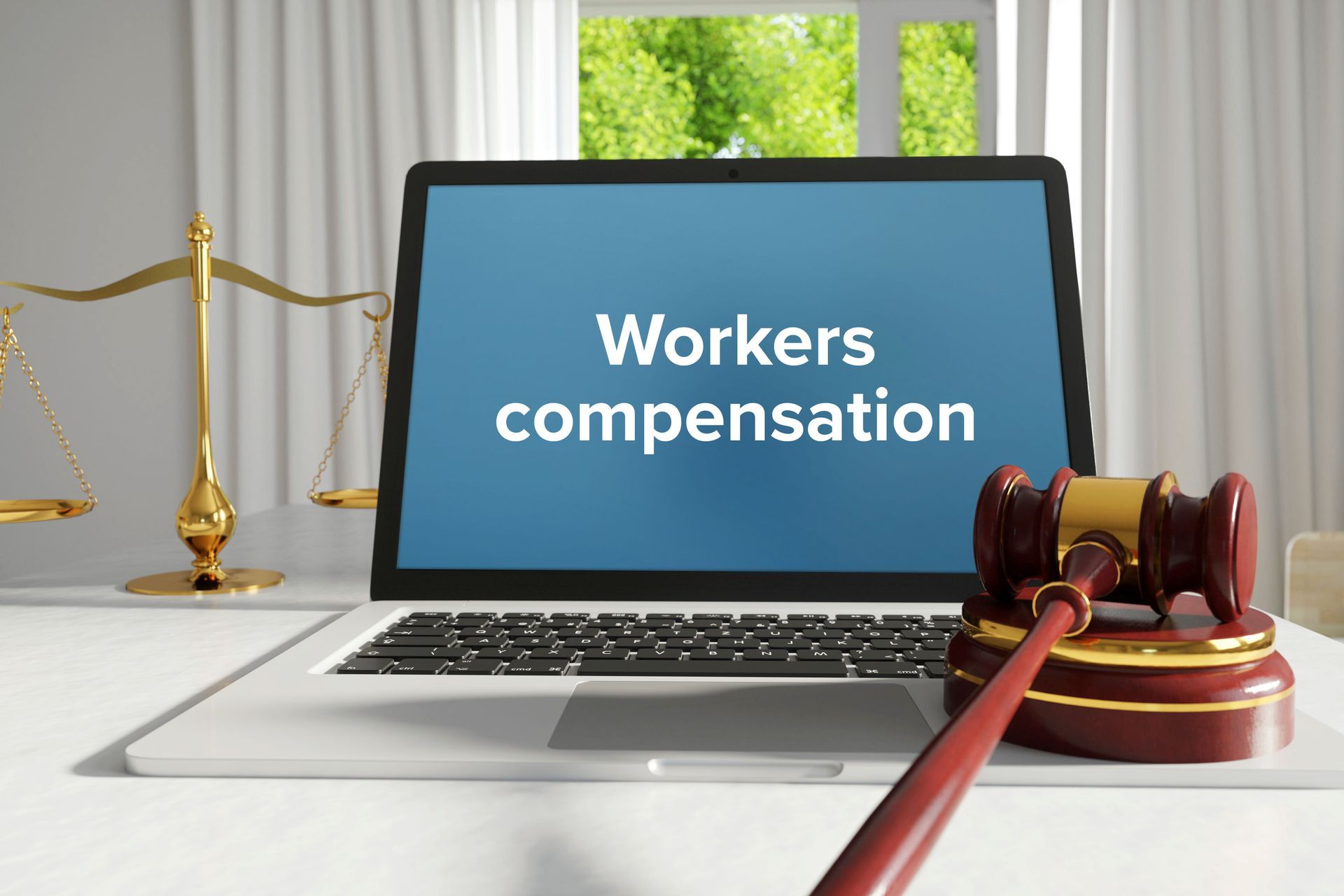 A workers’ compensation attorney's laptop on a desk in the office next to a scale and a gavel.