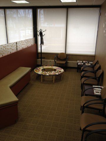 A waiting room with a round table and chairs and a bench at Advocare Washington Ave Pediatrics in Bergenfield, NJ