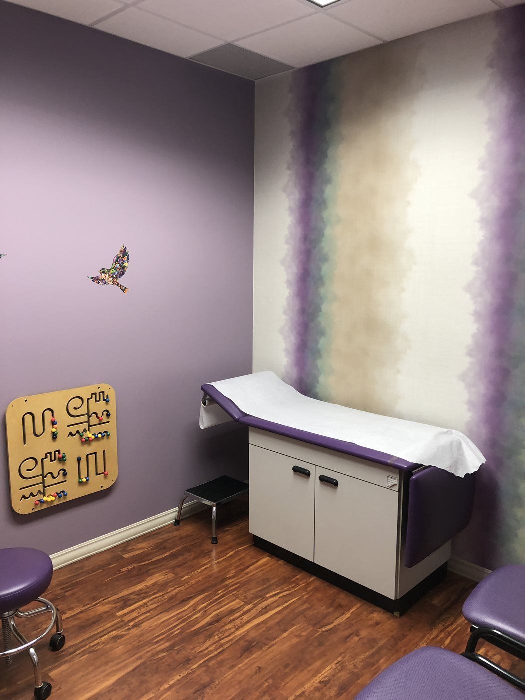 A doctor 's office with purple walls and a purple table at Advocare Washington Ave Pediatrics in Bergenfield, NJ