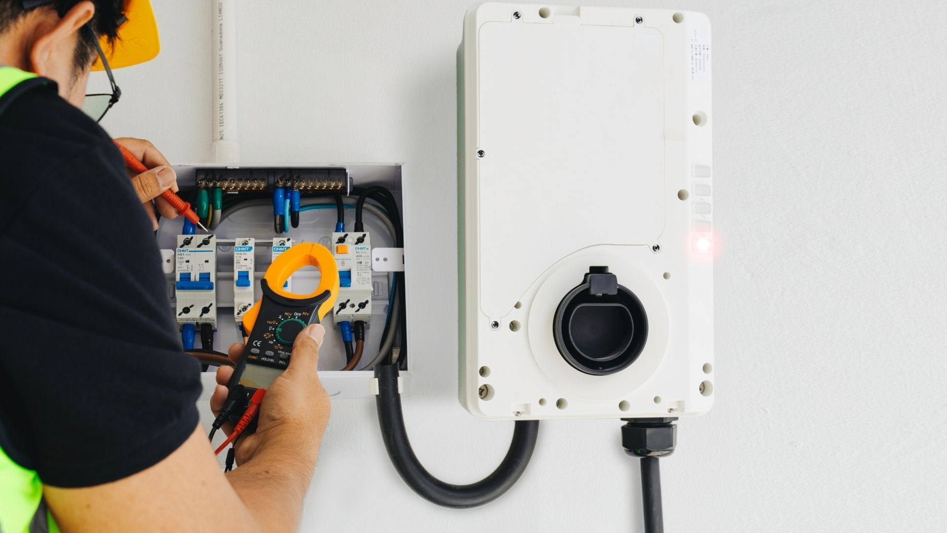 Person using a multimeter to test electrical wiring in a panel.