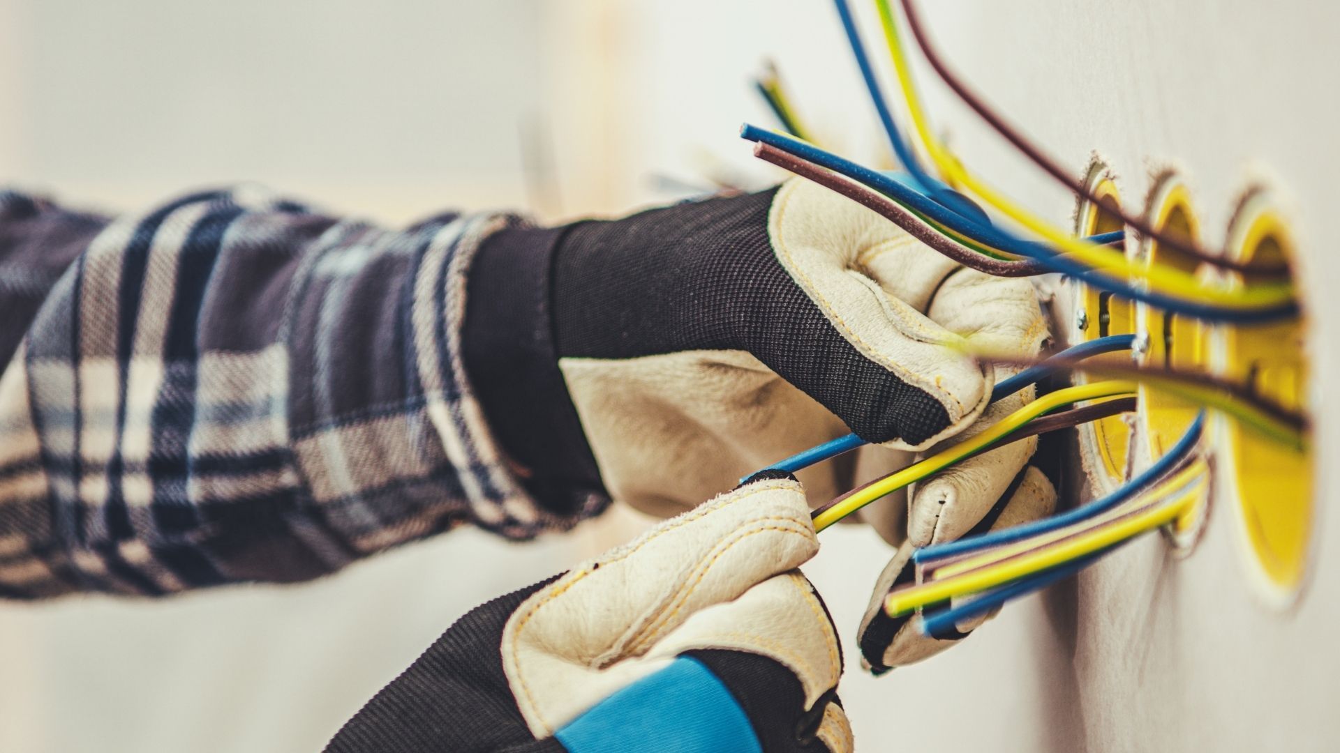 Person using a multimeter to test electrical wiring in a panel.