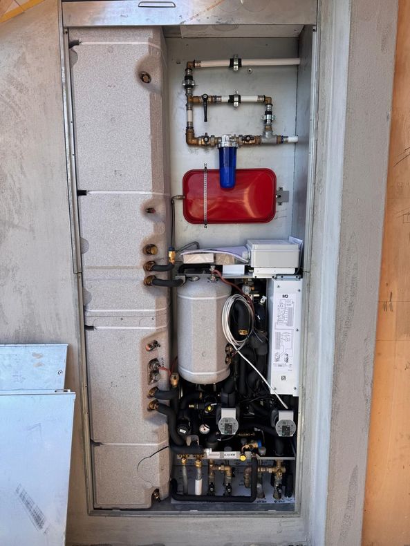 Un radiatore bianco con valvola termostatica annessa, installato a ridosso di una parete sotto il davanzale di una finestra.