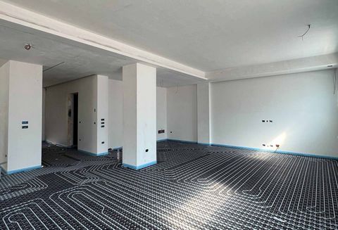 Un radiatore bianco con valvola termostatica, montato a parete sotto il davanzale di una finestra.