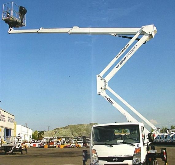Un carrello elevatore bianco con cestello sollevato si staglia contro un cielo azzurro in un'area industriale.