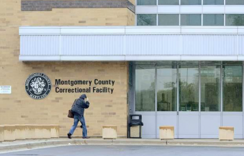 A man is walking in front of a montgomery county correctional facility.