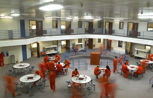A group of people are sitting at tables in a prison