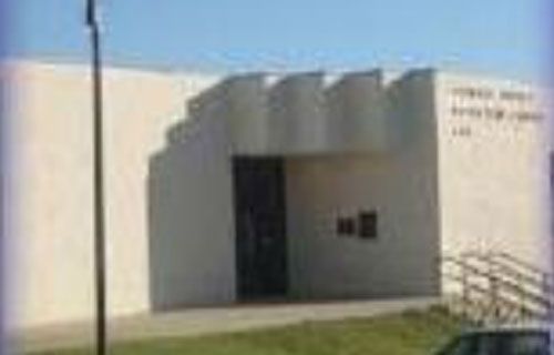 A white building with a car parked in front of it.