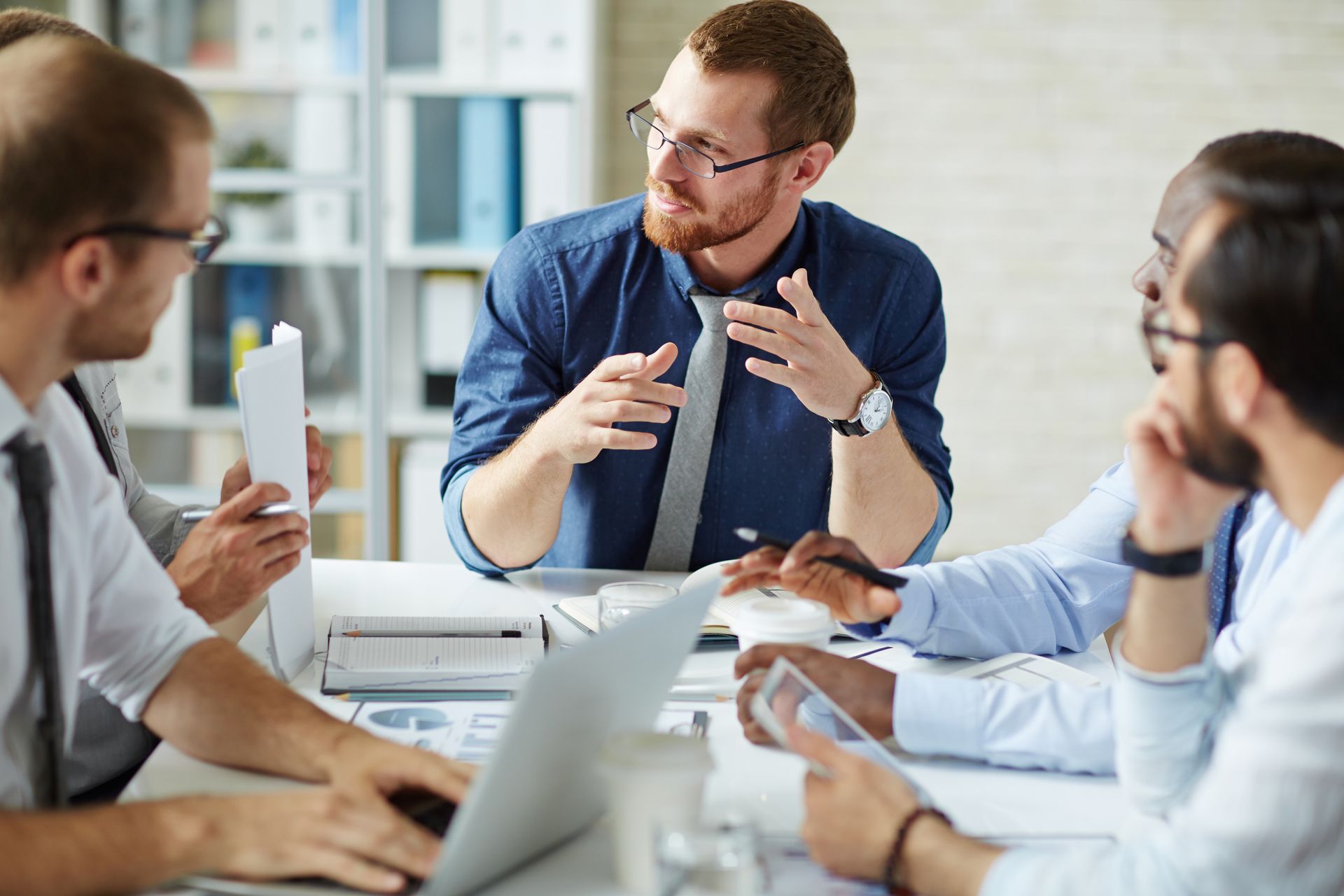 A group of men are sitting around a table having a meeting.